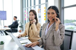 female operator agent with headsets and her team working in a call center customer service office.