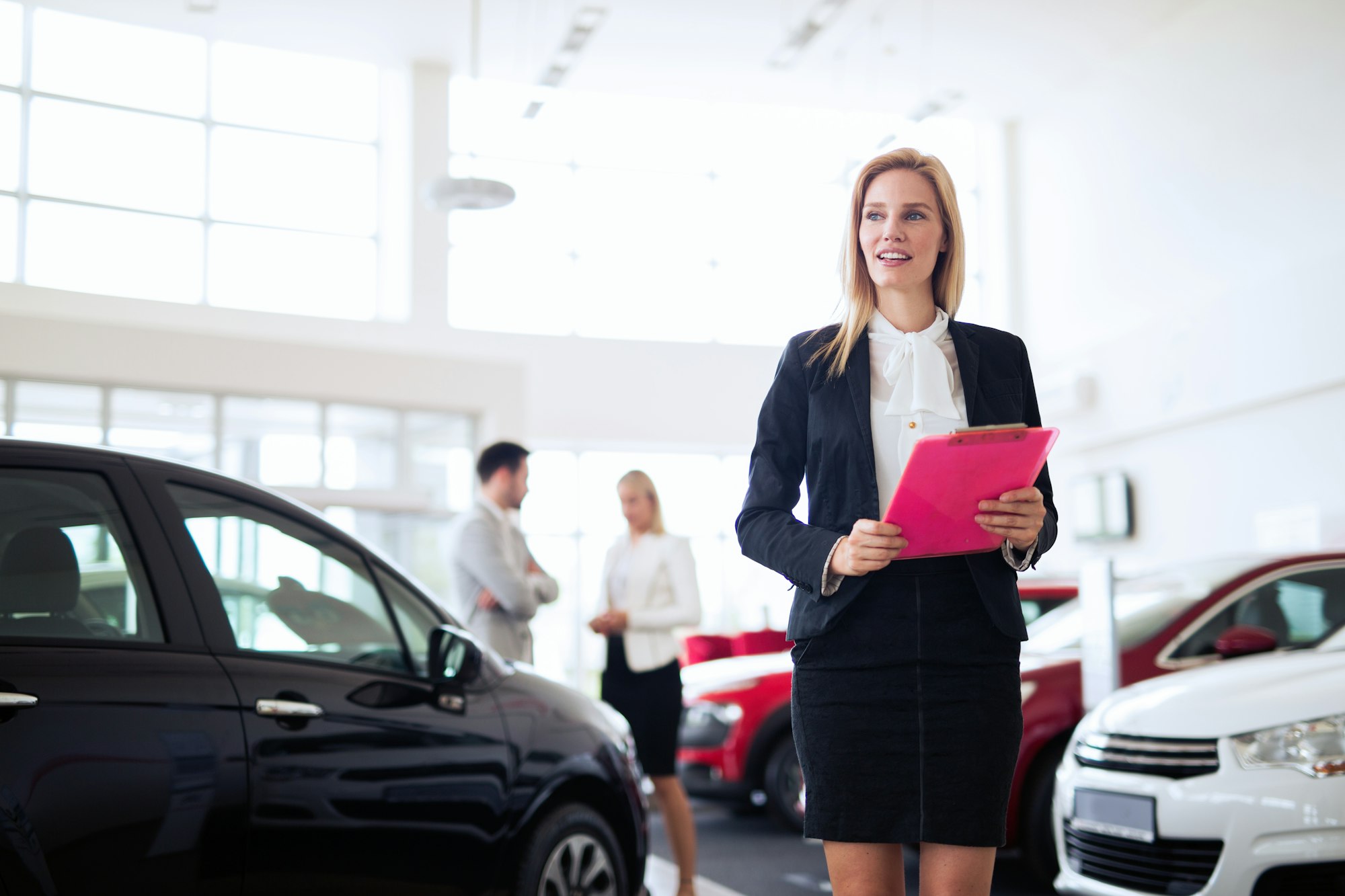 Young female car sales consultant working in showroom