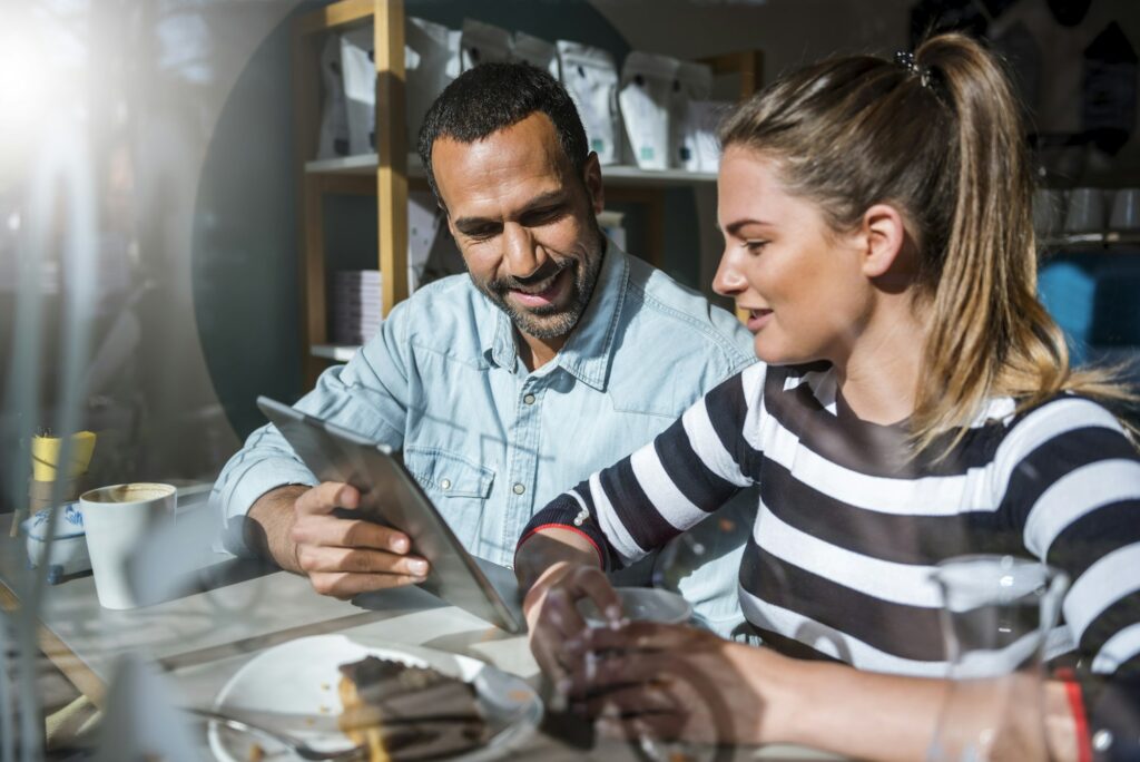 Young woman and man sharing tablet in a cafe