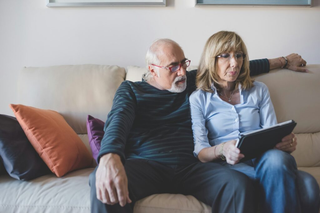 Middle-age couple sitting couch using tablet